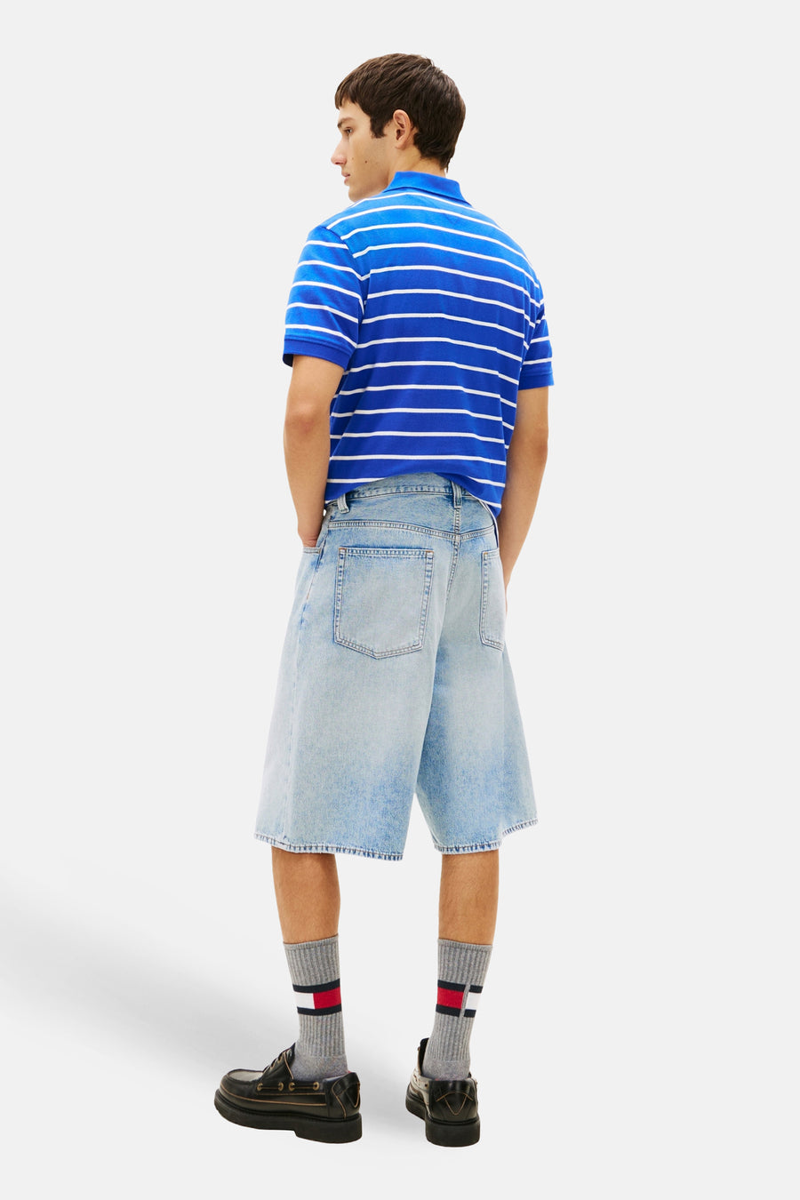 Short en jean en denim bleu moyen, de TOMMY JEANS, à jambes larges et poches apparentes, porté avec un polo rayé.