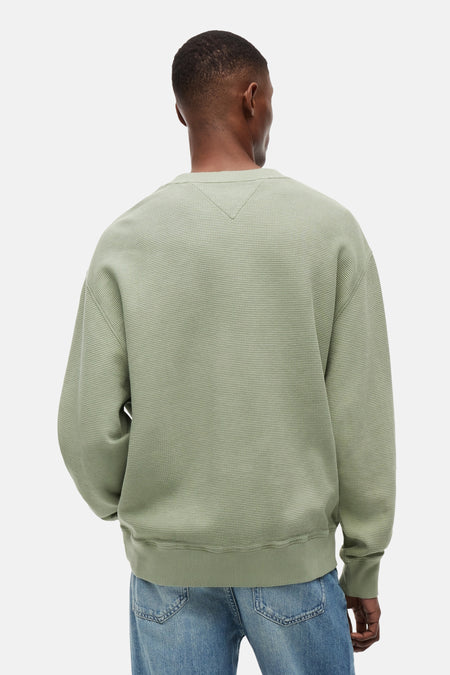 Groene sweater met ronde hals van TOMMY JEANS, met wafeltextuur en V-stiksel in de nek, op de rug gezien op een man.