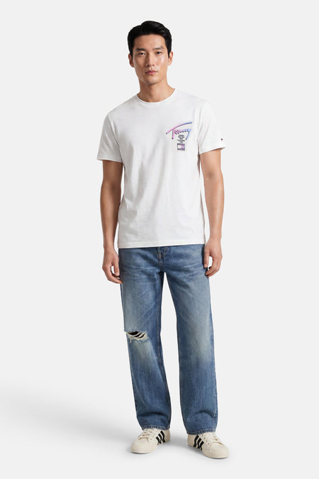 Witte korte mouwen T-shirt van TOMMY JEANS met kleurrijk logo op borst, gedragen met blauwe jeans en witte sneakers, front view