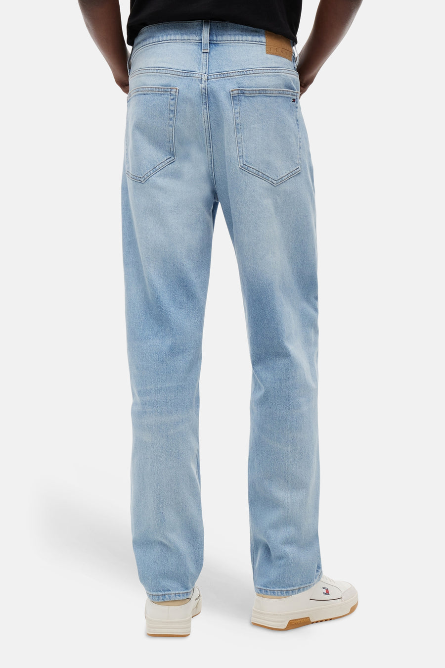 Jean fuselé bleu clair de TOMMY JEANS avec patch en cuir sur la ceinture et petit drapeau sur la poche arrière, vue arrière.