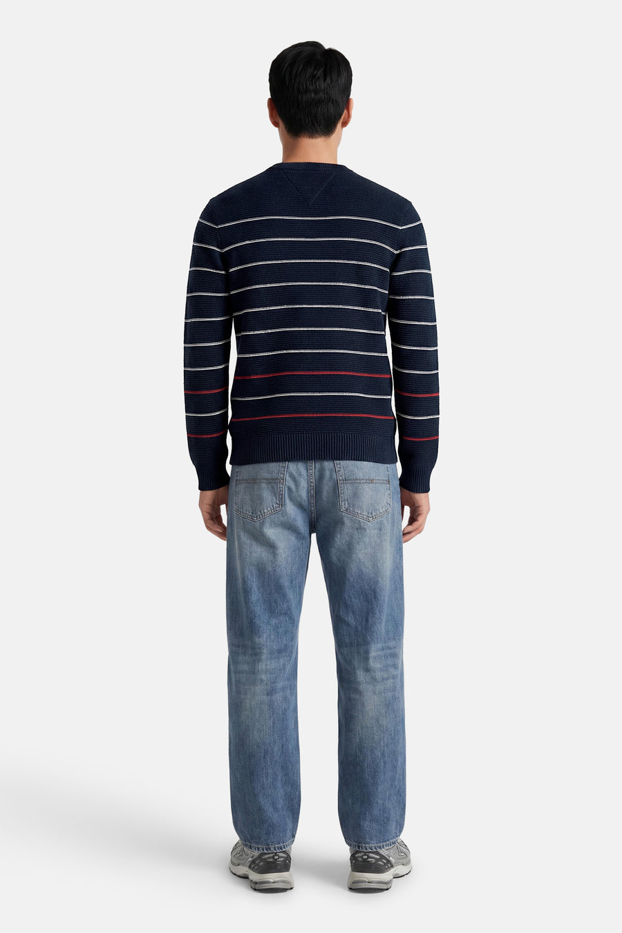 Blauwe ronde hals trui met witte en rode strepen van TOMMY JEANS, achterzijde weergegeven op model in lichtblauwe jeans