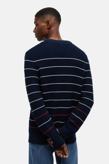 Pull bleu à col rond de TOMMY JEANS avec rayures blanches et rouges, texture côtelée, vu de dos.