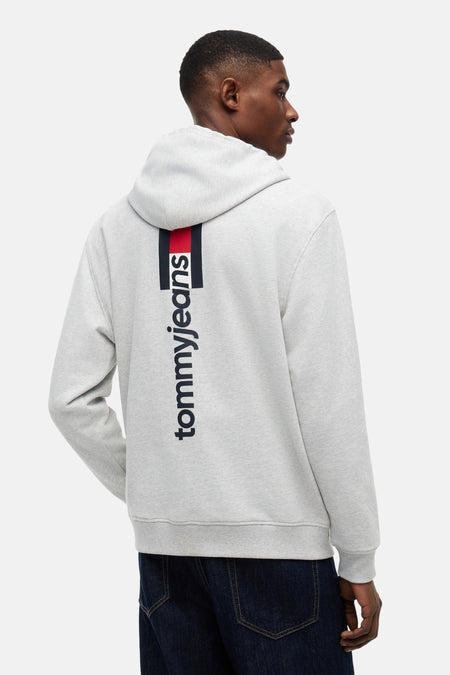 Grijze sweater met capuchon van TOMMY JEANS, met verticale rood-navy streep en 'tommyjeans' logo op de rug.