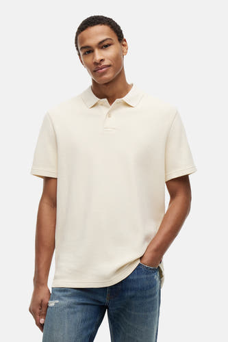 Ecru polo met fijne textuur van TOMMY JEANS, gedragen met blauwe jeans, front view