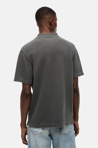 Zwarte polo van TOMMY JEANS, achterkant, met fijne textuur en korte mouwen, gedragen met lichtblauwe jeans