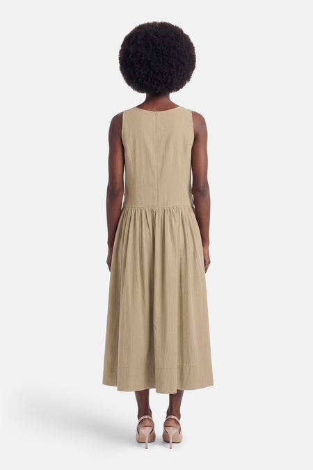 Beige mouwloos jurkje van ADORE, achterzijde met ruches en volle rok, model met afro kapsel en hoge hakken