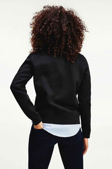 Pull à col rond noir de TOMMY JEANS, vue de dos, tissu lisse, modèle aux cheveux bouclés, bord de débardeur clair visible