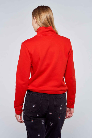 Rode ronde hals sweater van TOMMY JEANS, achterzijde met opstaande kraag en comfortabele pasvorm, gedragen met donkere jeans met hartjes borduursels.