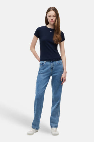 Blauw T-shirt van TOMMY JEANS met klein wit logo, gedragen met blauwe jeans en witte sneakers.