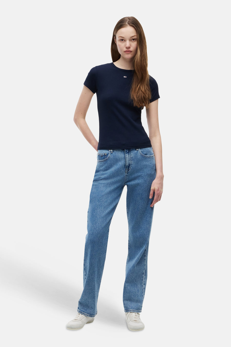 Blauw T-shirt van TOMMY JEANS met klein wit logo, gedragen met blauwe jeans en witte sneakers.