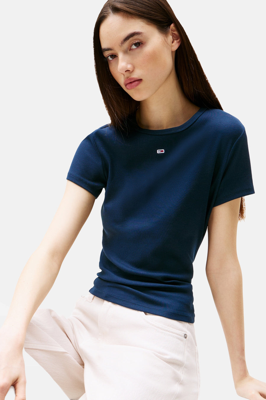 Blauw geribbeld T-shirt met korte mouwen van TOMMY JEANS met klein logo, gedragen door een model met een lichte broek.