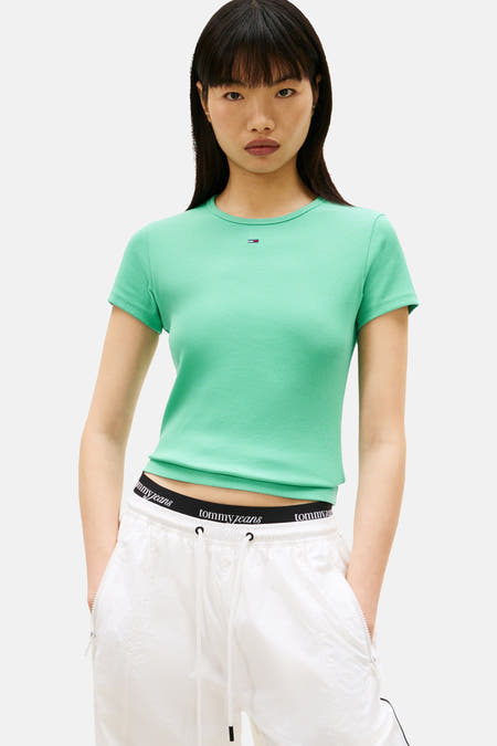 Groen T-shirt met korte mouwen van TOMMY JEANS, met ribstructuur, gedragen met witte joggingbroek met Tommy Jeans-band.
