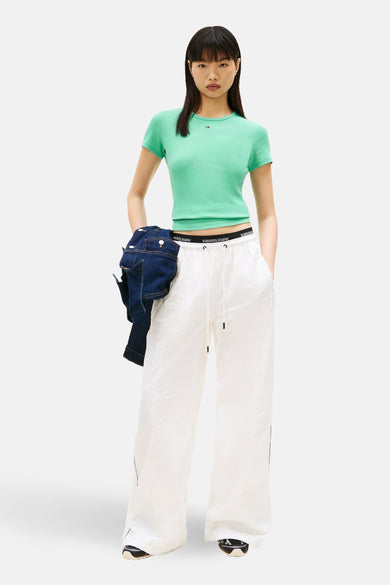 Groen T-shirt met korte mouwen van TOMMY JEANS, met een korte pasvorm en gedragen met witte joggingbroek.
