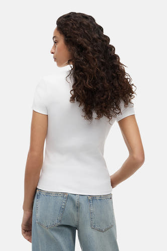 Wit geribd T-shirt met korte mouwen van TOMMY JEANS, van achteren gezien op een vrouw met lichtblauwe jeans.