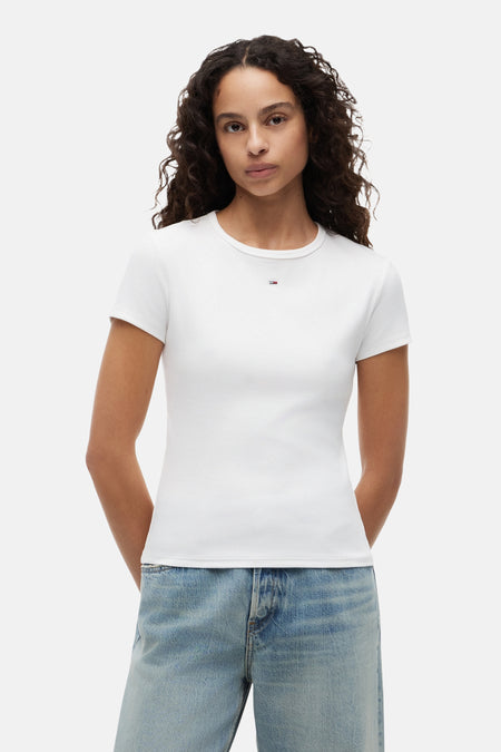 Wit geribbelde T-shirt van TOMMY JEANS met klein logo op de borst, gedragen door een model met een lichte spijkerbroek.