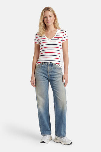 Multicolor gestreepte korte mouwen T-shirt van TOMMY JEANS, met V-hals en klein logo, gedragen met lichtblauwe jeans en witte sneakers, front view.