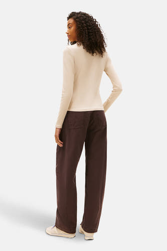 Beige T-shirt met lange mouwen van TOMMY JEANS, achterkant weergegeven, gecombineerd met bruine broek en crèmekleurige schoenen.