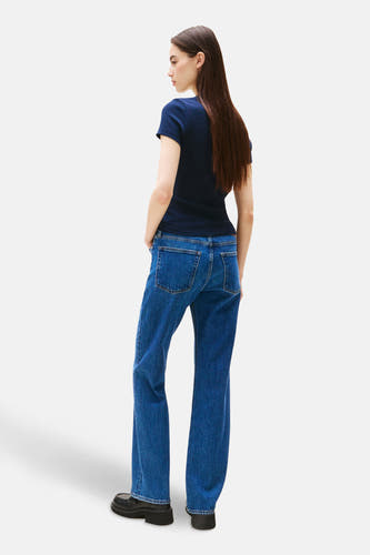 Blauw T-shirt met korte mouwen van TOMMY JEANS, gezien van achteren, met lange bruine haren en blauwe jeans.
