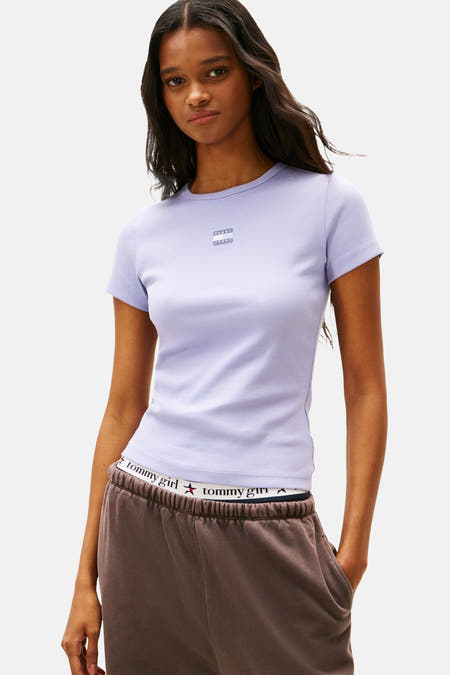 Paars T-shirt met korte mouwen van TOMMY JEANS, met ribstructuur en een model in bruine joggingbroek.

