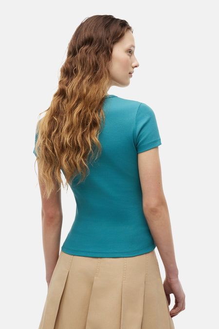 Geribbeld groen T-shirt van TOMMY JEANS, met korte mouwen, van achteren gedragen door een model op een beige rok.