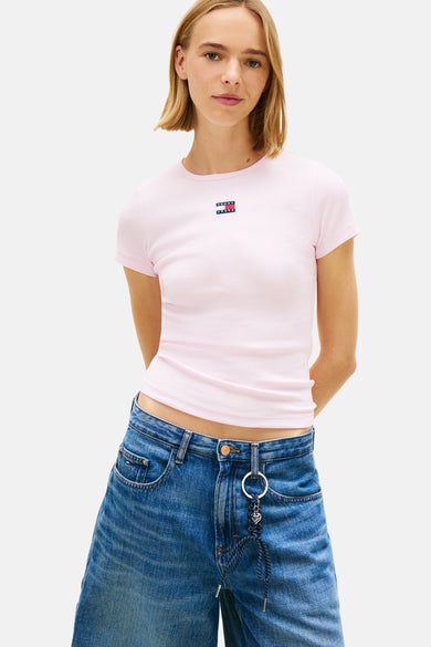 T-shirt rose à manches courtes TOMMY JEANS, couleur unie, porté avec un bermuda en jean et des chaussettes blanches.