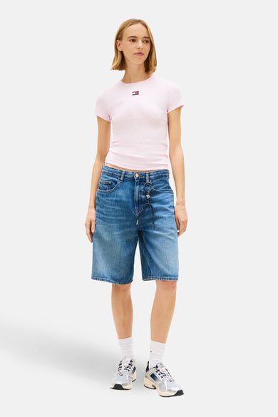 Roze T-shirt met korte mouwen van TOMMY JEANS, effen kleur, gedragen met denim bermuda en witte sokken.
