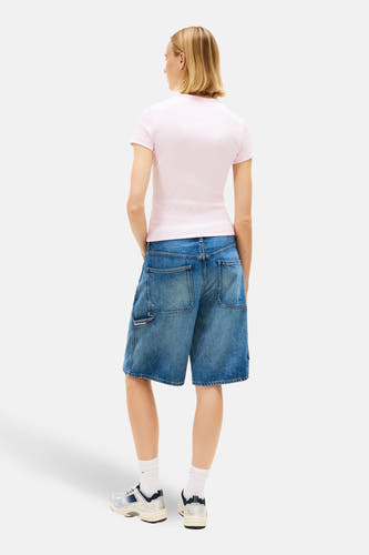 Roze T-shirt met korte mouwen van TOMMY JEANS, met casual styling en gedragen met blauwe denim shorts en witte sneakers.
