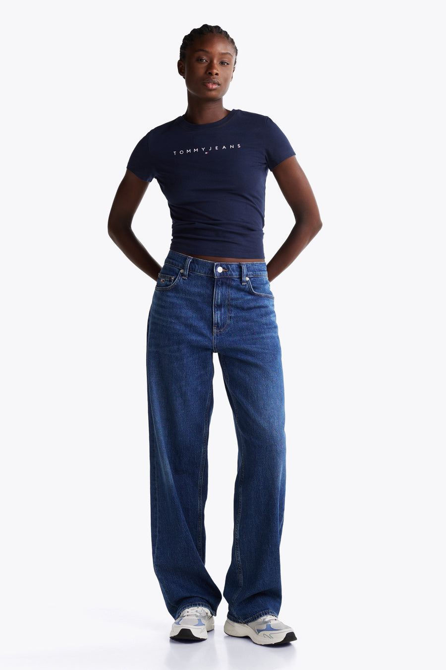 Blauw T-shirt met korte mouwen van TOMMY JEANS, met witte logo-opdruk, gecombineerd met wijde jeans en sneakers.