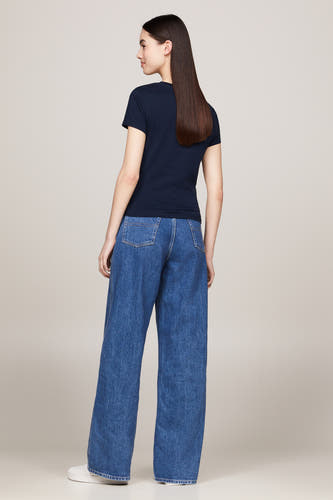 Blauw T-shirt met korte mouwen van TOMMY JEANS, gecombineerd met wijde jeans en witte sneakers.