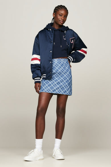 Blauwe geruite korte rok van TOMMY JEANS, gecombineerd met een navy hoodie en bomberjack.