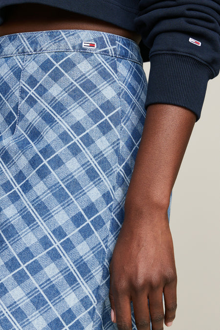 Blauwe korte rok van TOMMY JEANS met lichtblauw diagonaal ruitpatroon en klein logo op de tailleband, gedragen met een donkerblauwe trui.