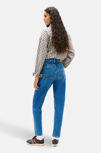 Middenblauwe mom jeans van TOMMY JEANS, met lange krullen en een geruit overhemd.

