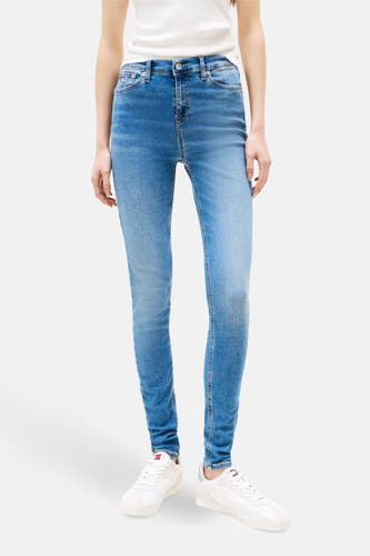 Skinny jeans in middenblauw denim van Tommy Jeans, met witte sneakers.
