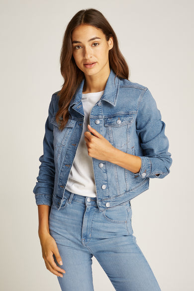 Lichtblauwe denim jeansjas van TOMMY JEANS, gecombineerd met een witte top en bijpassende jeans.
