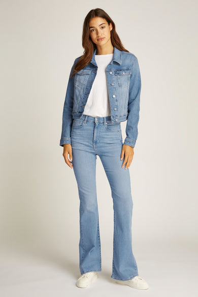 Jeansjas van lichtblauw denim van TOMMY JEANS, gedragen met een wit T-shirt en lichtblauwe jeans met uitlopende pijpen.