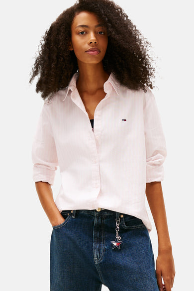 Roze overhemd met lange mouwen van TOMMY JEANS, met krijtstreepdessin en gedragen met een donkerblauwe jeans.

