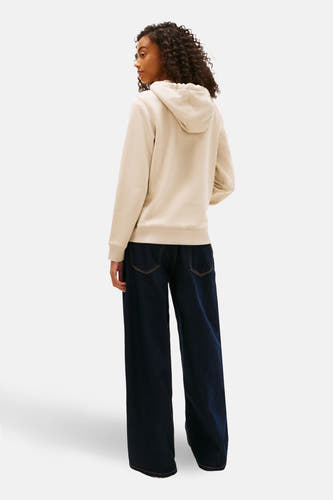 Beige sweater van TOMMY JEANS, met lange mouwen, capuchon en gecombineerd met een wijde, donkere jeans.