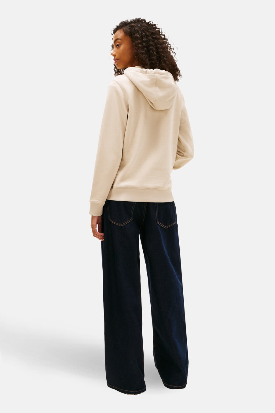 Beige sweater van TOMMY JEANS, met lange mouwen, capuchon en gecombineerd met een wijde, donkere jeans.