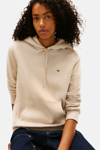 Beige sweater van TOMMY JEANS, met capuchon, lange mouwen en donkerblauwe jeans.
