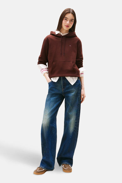 Bruine trui met ronde hals van TOMMY JEANS, gedragen over een wit overhemd met wijde blauwe jeans en bruine schoenen.