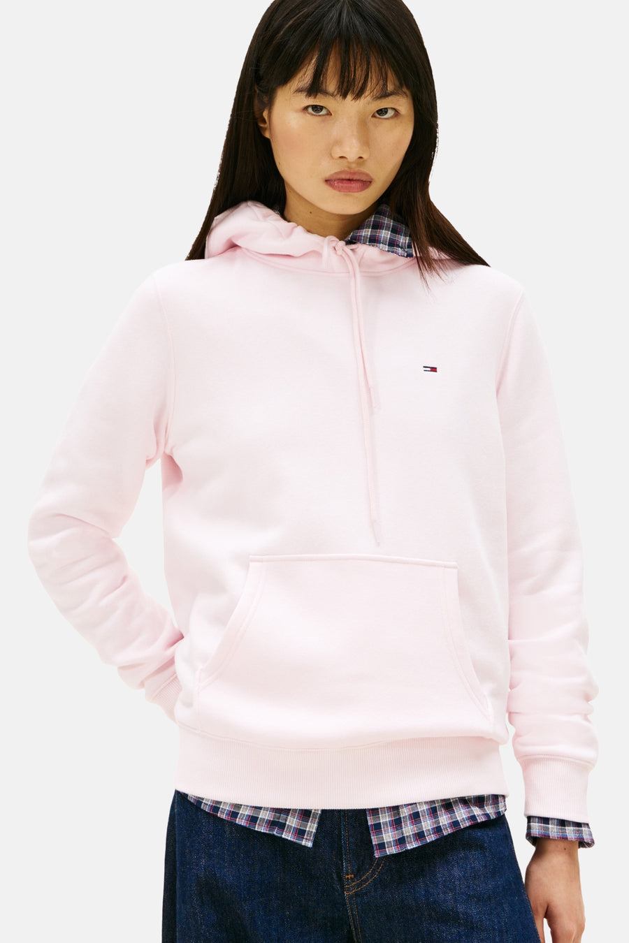Roze hoodie met Tommy Hilfiger logo, gedragen over een geruit overhemd.