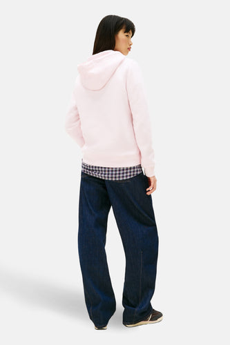 Aziatische vrouw in roze hoodie, geruite blouse en wijde jeans.