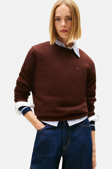 Bruine sweater van TOMMY JEANS, gedragen over een gestreept overhemd en met blauwe jeans.
