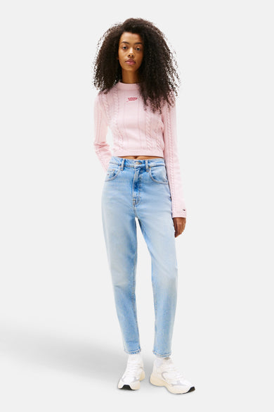 Lichtblauwe mom jeans van TOMMY JEANS, gecombineerd met een roze gebreide trui en witte sneakers.