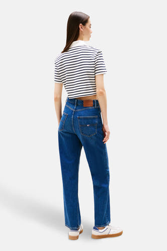 Jean droit bleu marine de Tommy Jeans, avec étiquette de marque sur l'arrière, associé à une polo rayée et des baskets blanches.