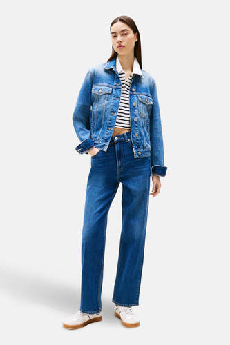 Jean bleu marine droit de TOMMY JEANS, associé à une chemise rayée, un blouson en denim et des baskets blanches.