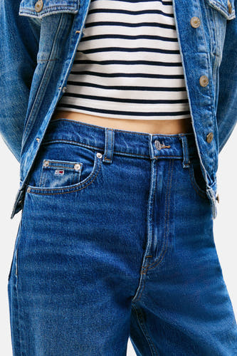 Jean droit bleu marine de TOMMY JEANS, associé à une chemise rayée et des baskets blanches.