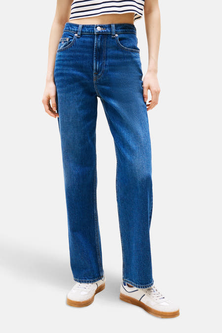 Jean bleu marine droit de TOMMY JEANS, associé à une chemise rayée et des baskets blanches avec des semelles brunes.