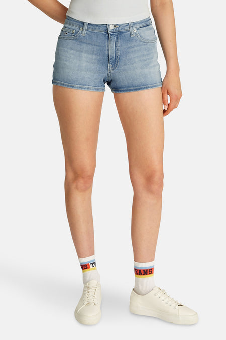 Korte lichtblauwe denim short van TOMMY JEANS, gedragen met witte sportschoenen en sokken met strepen en tekst.
