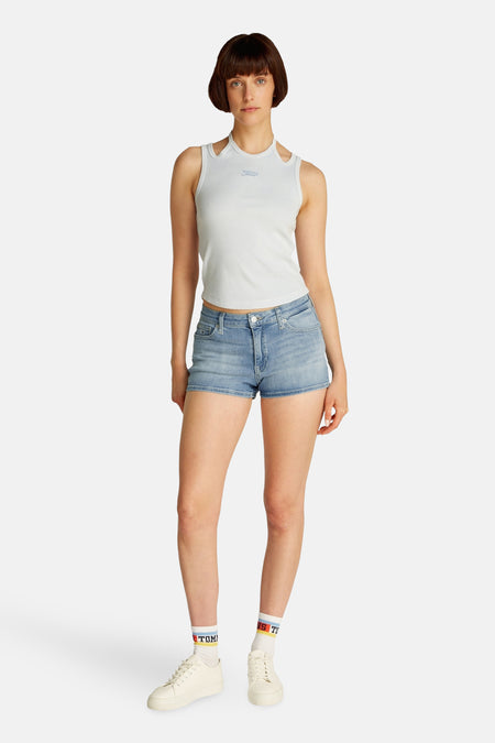Lichtblauwe denim short van TOMMY JEANS, gedragen met een wit ribtopje en witte sneakers met korte sokken.
